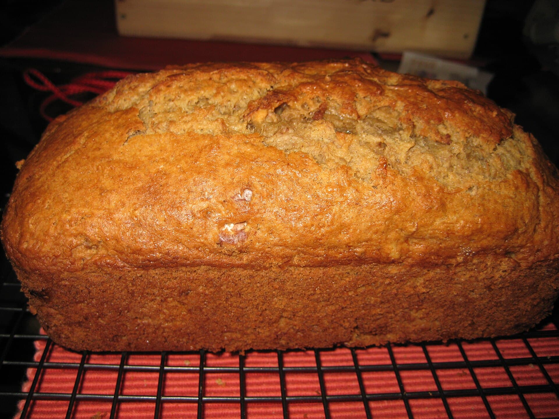 A golden-brown loaf of banana bread cooling on a wire rack.